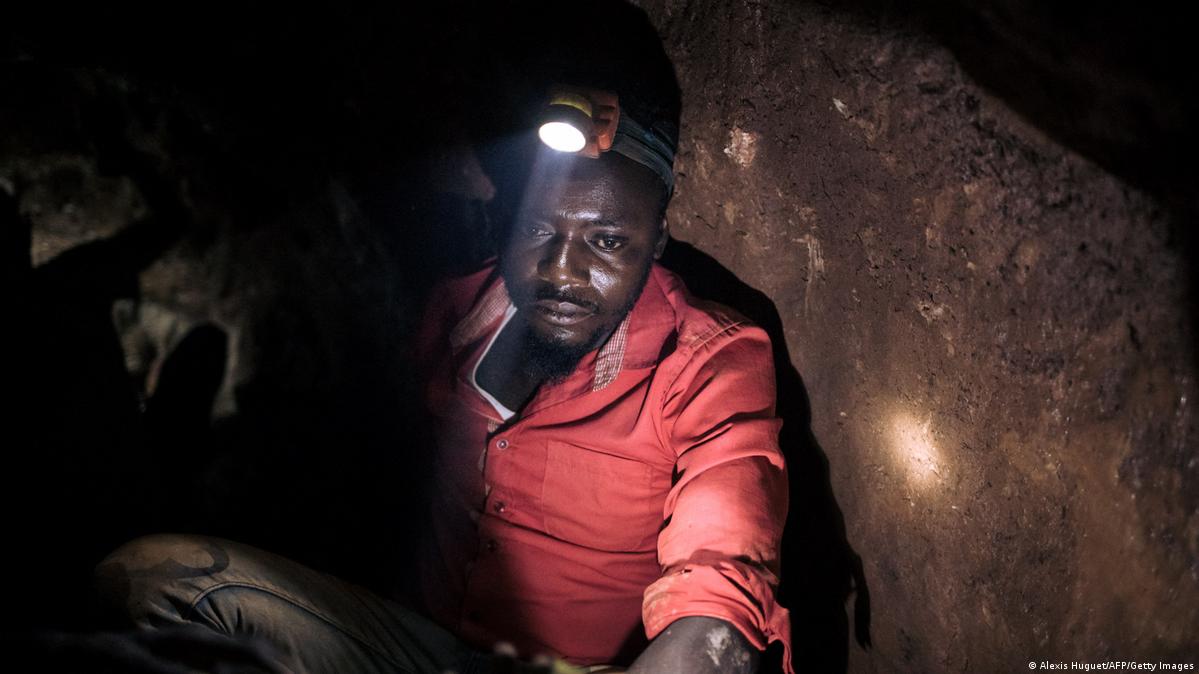 A gold miner wearing a red shirt and a headlamp