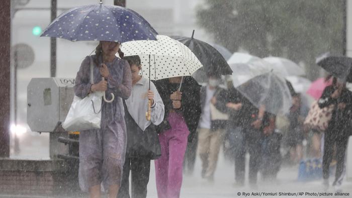 Personas en la calle se protegen con paraguas de las fuertes lluvias.