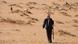 A man walks toward livestock in the Saudi desert. A man walks toward livestock in the Saudi desert.