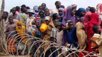 Somalis stand behind barbed wire to receive aid