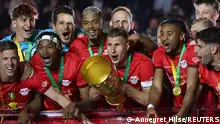 RB Leipzig-Kapitän Willi Orbán mit dem Pokal, umringt von seinen Teamkollegen 