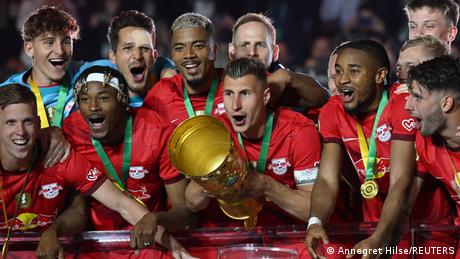 RB Leipzig-Kapitän Willi Orbán mit dem Pokal, umringt von seinen Teamkollegen 