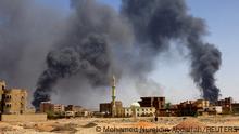 FILE PHOTO: A man walks while smoke rises above buildings after aerial bombardment, during clashes between the paramilitary Rapid Support Forces and the army in Khartoum North, Sudan, May 1, 2023. REUTERS/Mohamed Nureldin Abdallah/File Photo