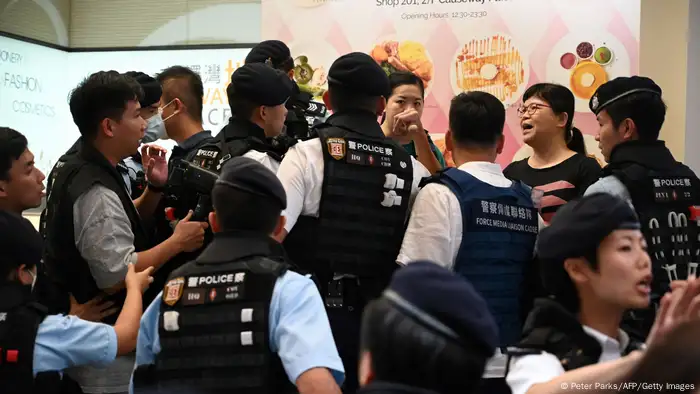 香港记者协会前主席麦燕庭（图右上二）在傍晚6点多现身铜锣湾，在一家商场外遭到警方盘查，几分钟后被警察带走。香港记协6月5日透过公开声明表示，记协前主席兼法广特约记者麦燕庭在湾仔警署被扣留至晚上11时始获释，但未获告知被控任何罪行。