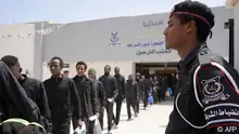 07/05/2023 Migrants queue in front of a bus outside a deportation office in the Libyan capital Tripoli on May 7, 2023, before their deportation. (Photo by AFP)