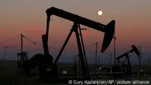 FILE - In this June 8, 2017, file photo, oil derricks are busy pumping as the moon rises near the La Paloma Generating Station in McKittrick, Calif. The U.S. is on pace to leapfrog both Saudi Arabia and Russia as the world’s biggest oil producer. (AP Photo/Gary Kazanjian, File)