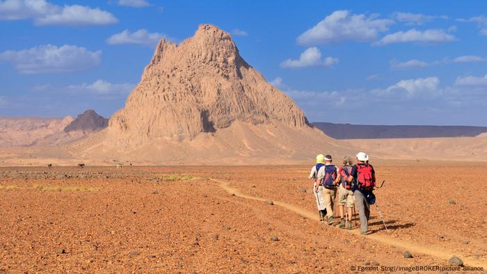 Tourists hiking in volcanic landscape, Hoggar Mountains, Ahaggar Mountains, Wilaya Tamanrasset