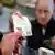 El propietario de la tienda Dot's Dollar More or Less de Mt. Lebanon, Pensilvania, entrega a un cliente un boleto de Mega Millions. (foto de referencia)