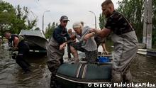 dpatopbilder - 07.06.2023, Ukraine, Cherson: Rettungskräfte evakuieren eine ältere Frau aus einem überfluteten Viertel in Cherson. Der Staudamm in der Stadt Nowa Kachowka war in der Nacht zum Dienstag in dem von Russland besetzten Teil des südukrainischen Gebiets Cherson zerstört worden. Die Fluten stiegen am Mittwoch in der Südukraine weiter an und zwangen Hunderte von Menschen zur Flucht aus ihren Häusern. Foto: Evgeniy Maloletka/AP +++ dpa-Bildfunk +++