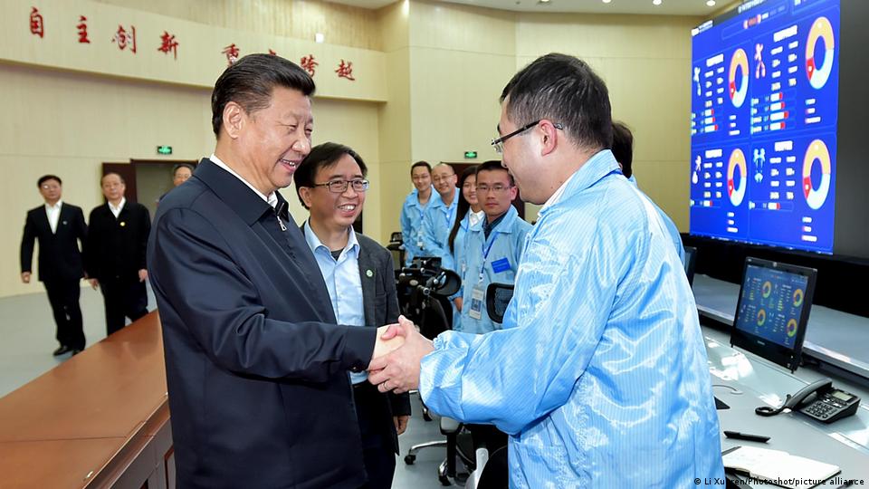 Chinese President Xi Jinping visits shakes hand with a scientist wearing a blue protective suit at the Spin Magnetic Resonance Laboratory at University of Science and Technology of China in Hefei, east China's Anhui Province