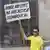 Ein Mann steht mit einem Schild vor einem besetztem Haus (Foto: DW)