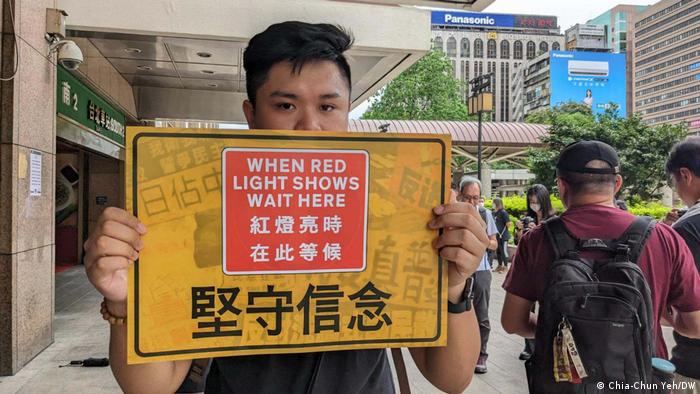 12日在台北车站参与“快闪”合唱活动的民众举著标语，强调“坚守信念”。