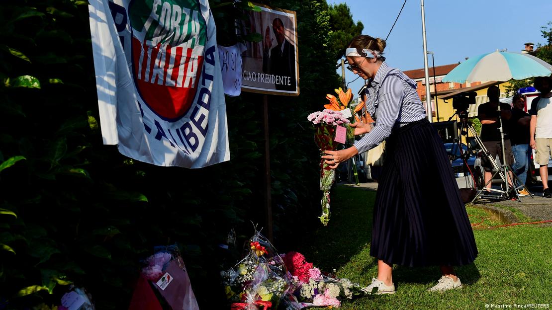 Una mujer deposita flores delante de la casa del ex primer minstro Silvio Berlusconi