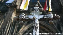 A cross superimposed on the Cologne cathedral