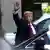 Former US President Donald Trump waving as he stands next to cars