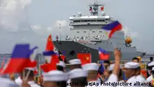 Members of the Philippine Coast Guard wave flags as they welcome the arrival of Chinese naval training ship, Qi Jiguang, for a goodwill visit at Manila's port, Philippines Wednesday, June 14, 2023. The Chinese navy training ship made a port call in the Philippines on Wednesday, its final stop on a goodwill tour of four countries as Beijing looks to mend fences in the region. (AP Photo/Basilio Sepe)