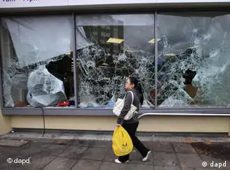 A woman walks past a damaged supermarket in Ealing, west London, after a night of rioting, Tuesday, Aug. 9, 2011. In London, groups of young people rampaged for a third straight night, setting buildings, vehicles and garbage dumps alight, looting stores and pelting police officers with bottles and fireworks into early Tuesday. The spreading disorder was an unwelcome warning of the possibility of violence during London's 2012 Summer Olympics, less than a year away. (Foto:Lefteris Pitarakis/AP/dapd)