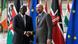 William Ruto shakes hands with Charles Michel as they stand in front of numerous flags