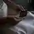 Mujer sentada con las manos en su regazo, sosteniendo una ecografía que muestra su embarazo.