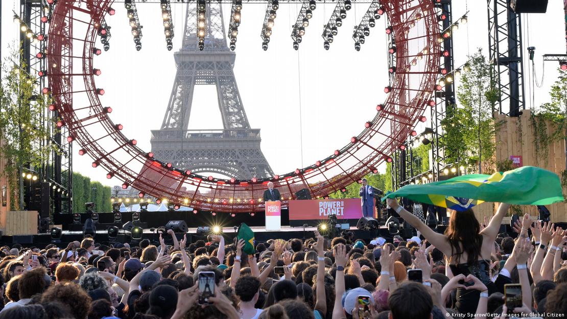 Multidão em festival em frente à Torre Eiffel, em Paris. Lula discursa no palco