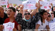 People lift placards as they shout slogans during a demonstration against the presence of illegal sub-Saharan migrants, in Sfax on June 25, 2023. Sfax, the second largest city in Tunisia, is the starting point for a large number of illegal migrants trying to reach Italy. (Photo by HOUSSEM ZOUARI / AFP) (Photo by HOUSSEM ZOUARI/AFP via Getty Images)