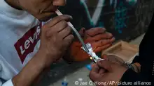 Two homeless addicts share a small piece of fentanyl in an alley in Los Angeles, Thursday, Aug. 18, 2022. Use of fentanyl, a powerful synthetic opioid that is cheap to produce and is often sold as is or laced in other drugs, has exploded. Two-thirds of the 107,000 overdose deaths in 2021 were attributed to synthetic opioids like fentanyl, the U.S. Centers for Disease Control and Prevention says. (AP Photo/Jae C. Hong)
