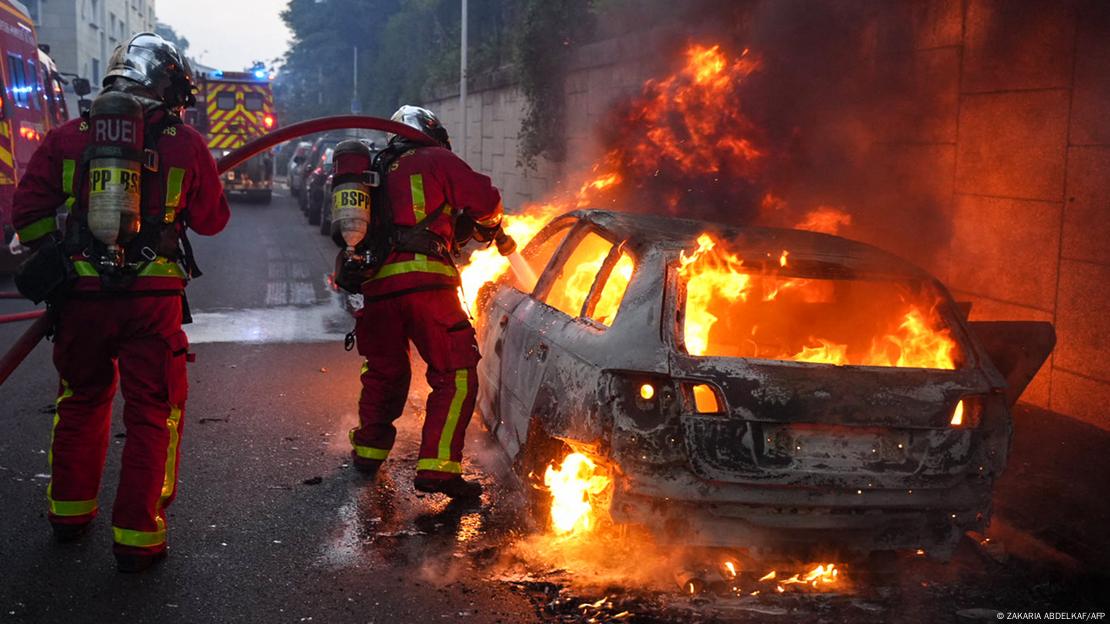 Feuerwehrleute löschen ein brennendes Auto 