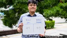 In this picture taken in Seoul on June 21, 2023, Hong Suk-min, an office worker, poses with a whiteboard showing his international age, 45, and Korean age, 47. From June 28, 2023 South Korea will use the international system that calculates age according to a person's actual date of birth, meaning everyone will officially become a year or two younger. It's confusing when a foreigner asks me how old I am as I know they mean international age, so I have to do some calculations, Hong Suk-min told AFP. (Photo by ANTHONY WALLACE / AFP) / To go with SKorea-politics-culture-age, FOCUS by Cat BARTON (Photo by ANTHONY WALLACE/AFP via Getty Images)