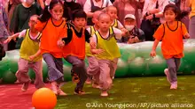 Children with shaved haircuts compete for the ball with kindergarten pupils under red lanterns during the Dongjasung (Little Monk) Soccer Match for Buddha's upcoming Birthday celebrations, at Chogye temple in Seoul, South Korea, Wednesday, May 24, 2023. The children with shaved haircuts have entered the temple to have an experience of monks' life for three weeks. (AP Photo/Ahn Young-joon)