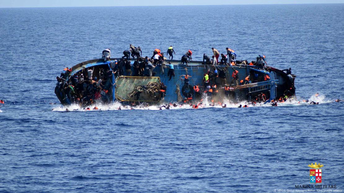 Un barco lleno de migrantes poco antes de hundirse.  La gente salta al agua.