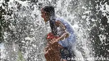 FILE PHOTO: Fernando Aguilar, from El Salvador, carries his eight year old daughter Dannesy through the jet streams of Gateway Fountains at Discovery Green to escape the hot weather on Father's Day in Houston, Texas, U.S., June 18, 2023. REUTERS/Adrees Latif/File Photo