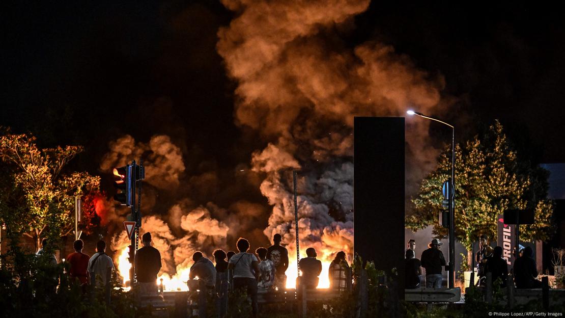 Menschengruppe vor brennenden Reifen