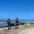 Libyen, Abu Qurain City | Einsatz gegen Flüchtlingsboot: Zwei Männer in Tarnuniform stehen am Strand, neben ihnen ein Pickup