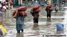 230705 -- LAHORE, July 5, 2023 -- Laborers carry vegetable sacks as they wade through flooded water after heavy monsoon rain in Lahore, Pakistan, on July 5, 2023. Photo by /Xinhua PAKISTAN-LAHORE-HEAVY RAIN-FLOOD Sajjad PUBLICATIONxNOTxINxCHN