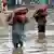 Laborers carry vegetable sacks as they wade through flooded water after heavy monsoon rain in Lahore, Pakistan