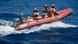 Ein rotes Schlauchboot mit Außenbordmotor und drei Personen auf dem Meer Ein rotes Schlauchboot mit Außenbordmotor und drei Personen auf dem Meer