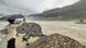 A man holding an umbrella over his head as he stands on the banks of swollen river Satluj in India A man holding an umbrella over his head as he stands on the banks of swollen river Satluj in India