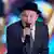 Ruben Blades mit Anzug und Hut singt ins Mikrofon
