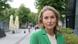 A cientista política Margarita Šešelgytė aparece de blazer verde, olhando para a câmera, em uma rua de Vilnius, capital da Lituânia.