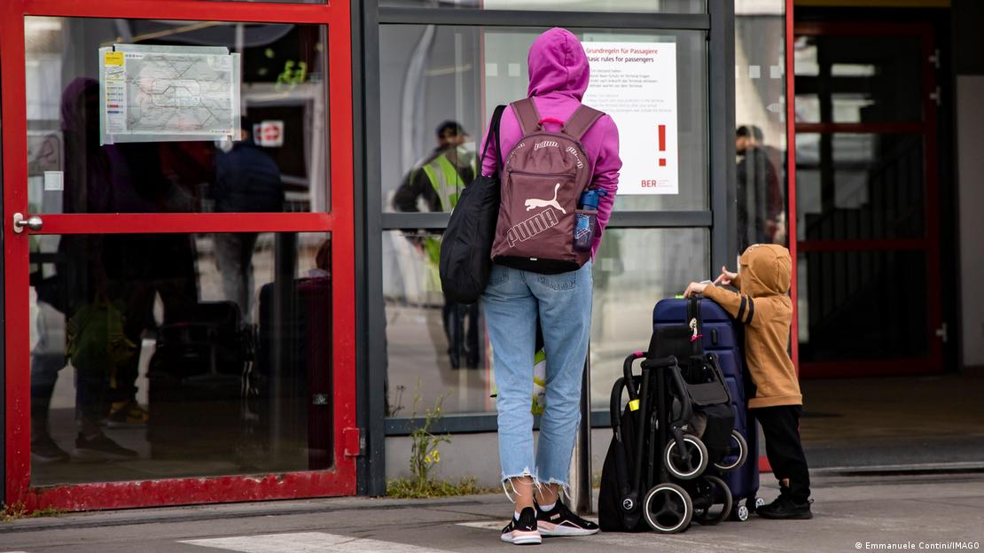 Молодая мать с ребенком у центр приема беженцев из Украины в бывшем берлинском аэропорту Тегель