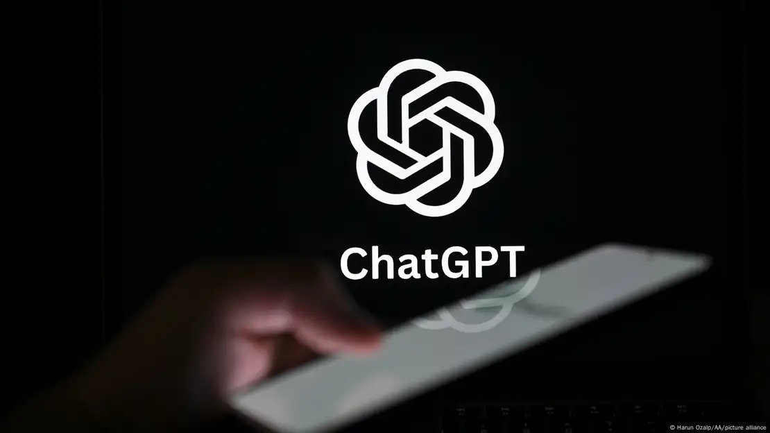 A hand holds a phone in front of the word's ChatGPT and the company's logo