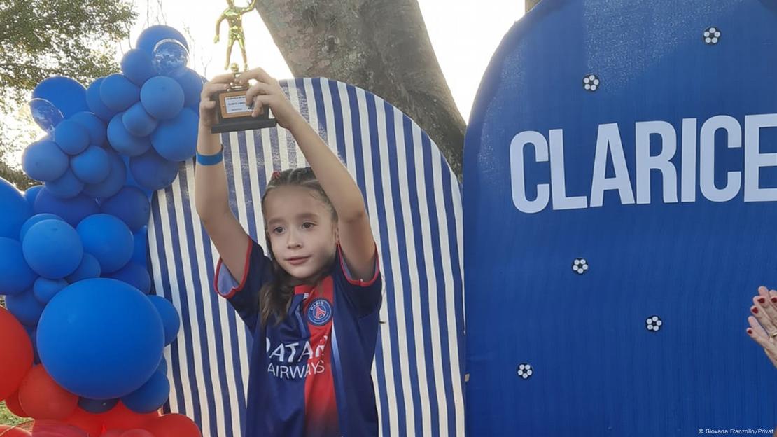 Criança segura um troféu durante sua festa de aniversário, com temática de futebol