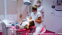 Symbolfoto fuer Zahnaerztin bei Behandlung eines Patienten auf dem Zahnarztstuhl