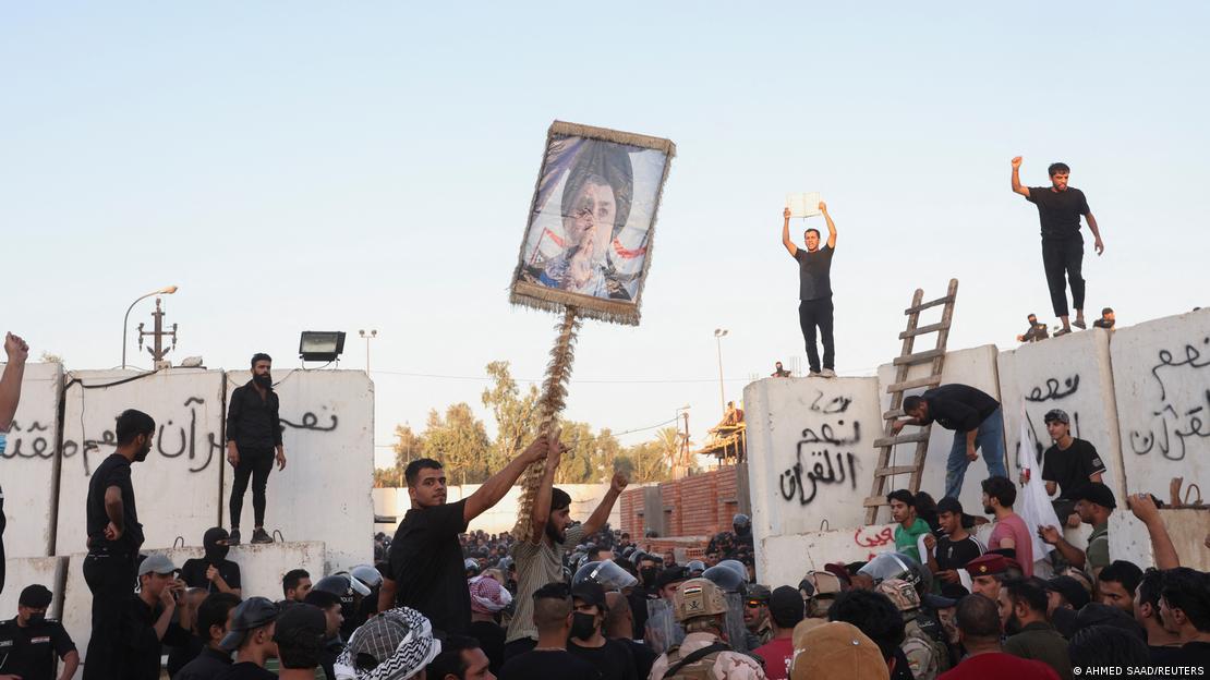 Iraqi protesters clash with security forces as they gather near the Swedish embassy in Baghdad, with one demonstrator carrying a sign showing a picture of Muqtada al-Sadr