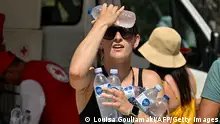 20/07/2023**A woman cools off with cold bottles of water, distributed by the hellenic red cross organization near the entrance of the Acropolis archeological site in Athens on July 20, 2023, as the country is hit by a new major heatwave. Archaeological sites, including the Acropolis, will be closed during the hottest hours of the day due to the new heatwave, Greece announced on July 20. (Photo by Louisa GOULIAMAKI / AFP) (Photo by LOUISA GOULIAMAKI/AFP via Getty Images)