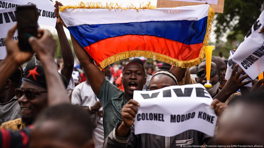 Homem segura uma bandeira da Rússia em meio a uma multidão