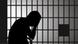 A man sits in the dark on the bed in his prison cell A man sits in the dark on the bed in his prison cell