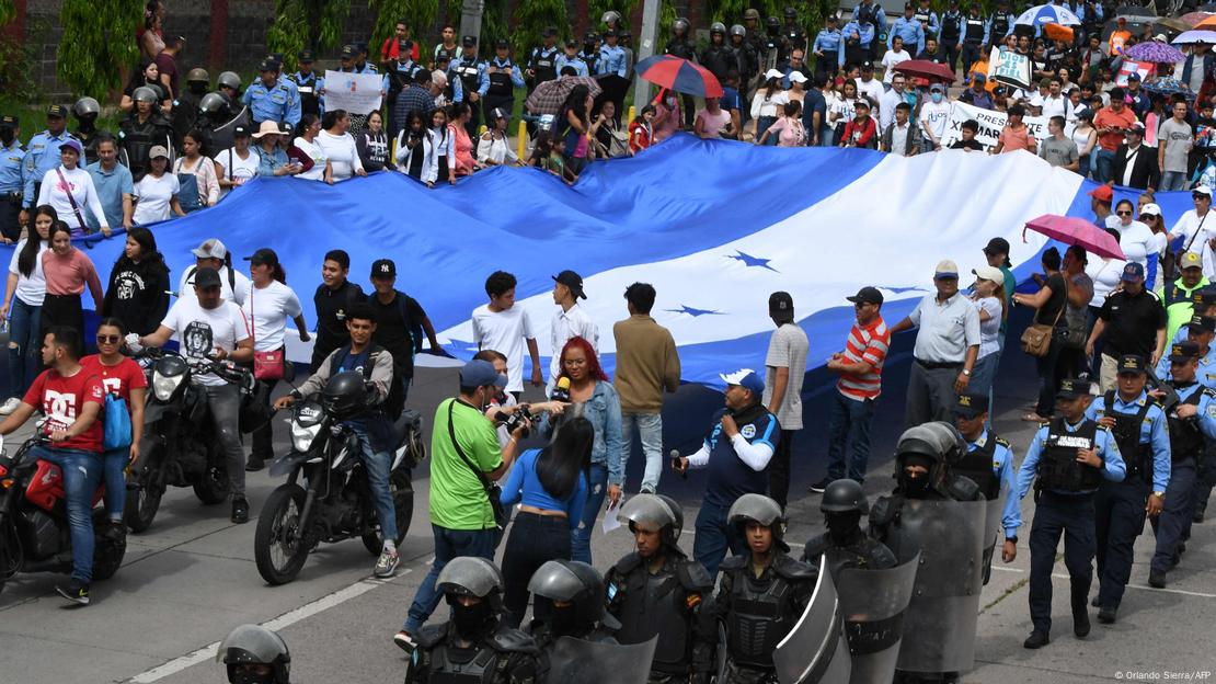 Foto de personas que marchan con una bandera de Honduras