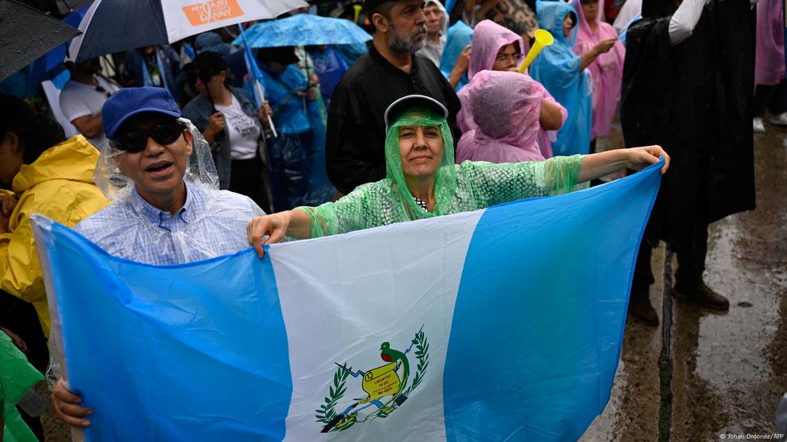 Foto de personas que protestan con una bandera de Guatemala Foto de personas que protestan con una bandera de Guatemala