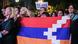 A group of Armenians stand holding a flag during a protest